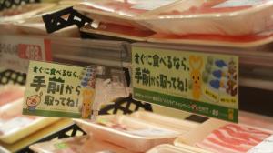 パック詰めされた精肉が並ぶ棚に黄緑色の注意書きが貼ってある写真