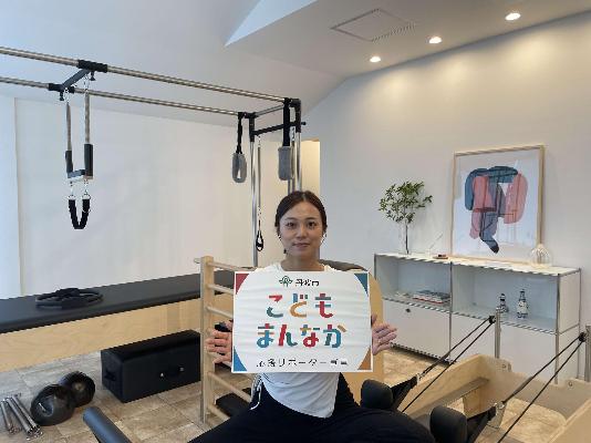 女性が笑顔で「こどもまんなか」のパネルを持っている様子
