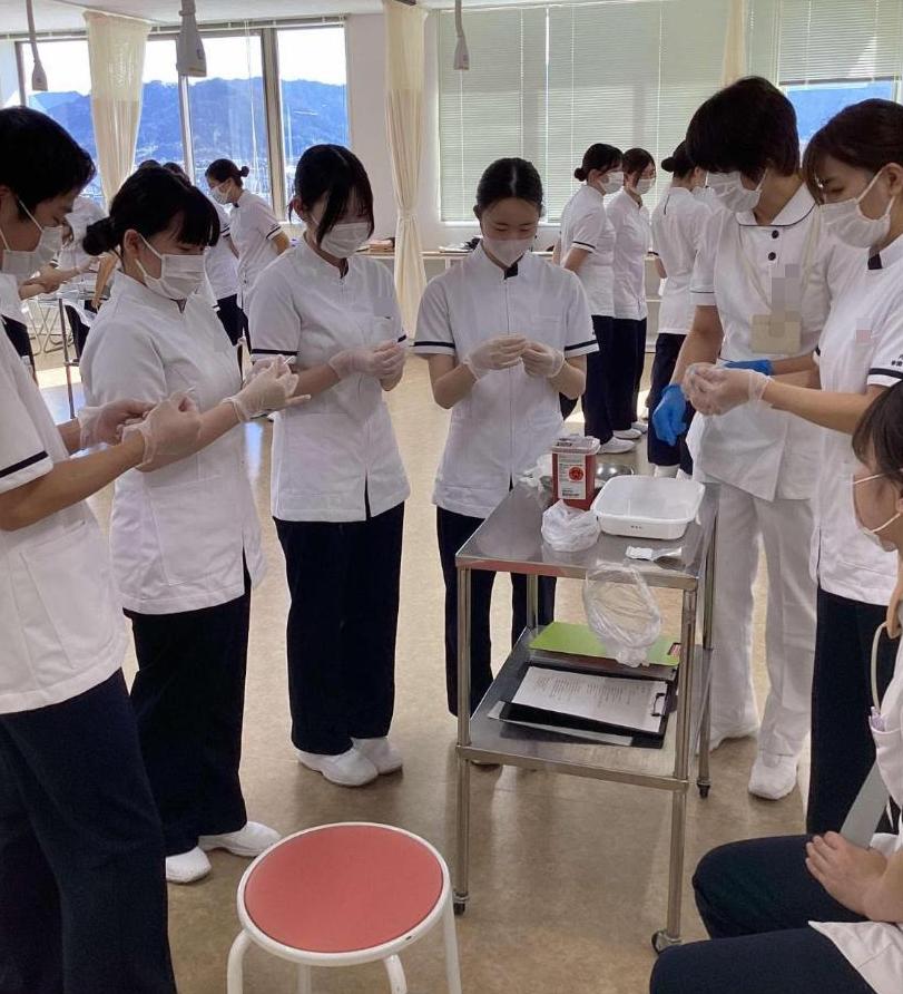 教員の話を聞きながら注射器の準備をしている学生たちの写真