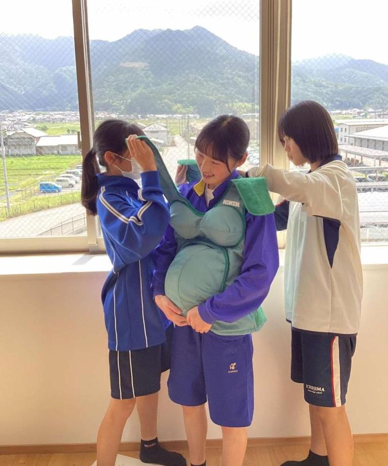 妊婦体験スーツを着せている中学生達と着せてもらっている中学生の写真