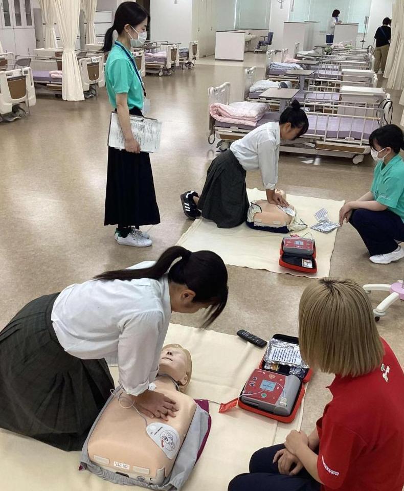 参加者が心臓マッサージを体験しているところの写真