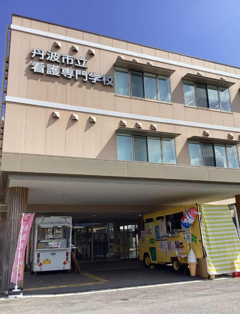 キッチンカー2台が学校の玄関前に駐車しているところの写真