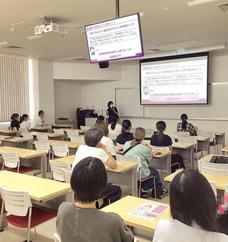 視聴覚室で看護師についての説明を聞いている参加者たちの写真