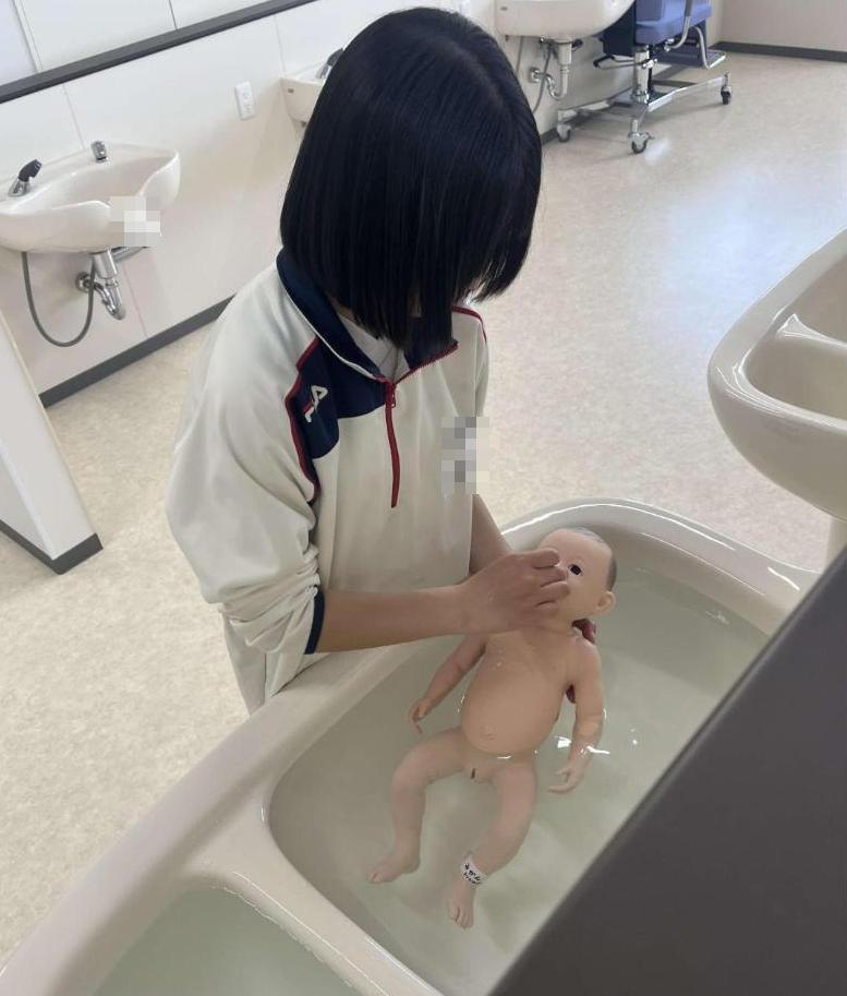 赤ちゃん人形を沐浴している中学生の写真