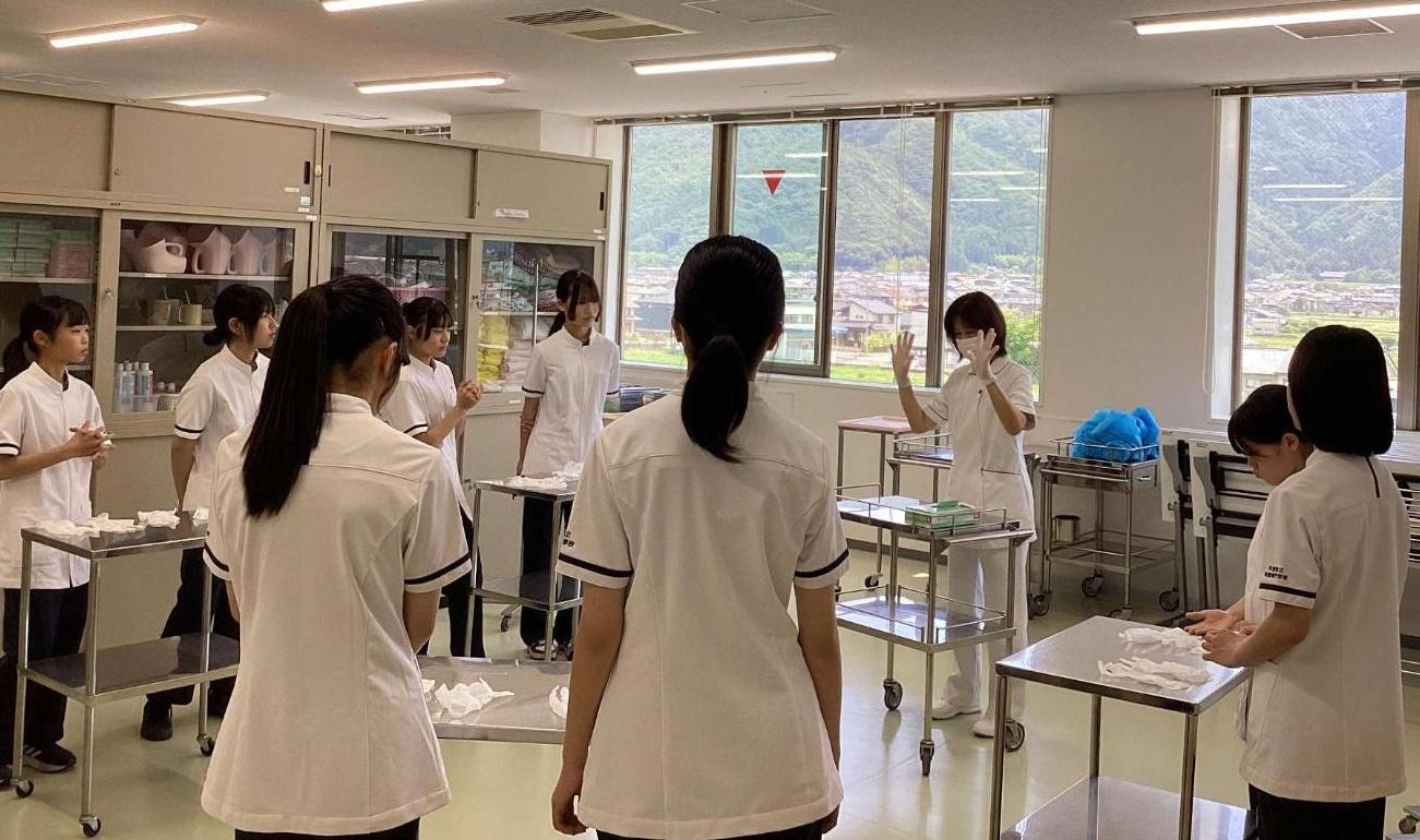 手袋の着用のしかたを聞いている中学生達の写真