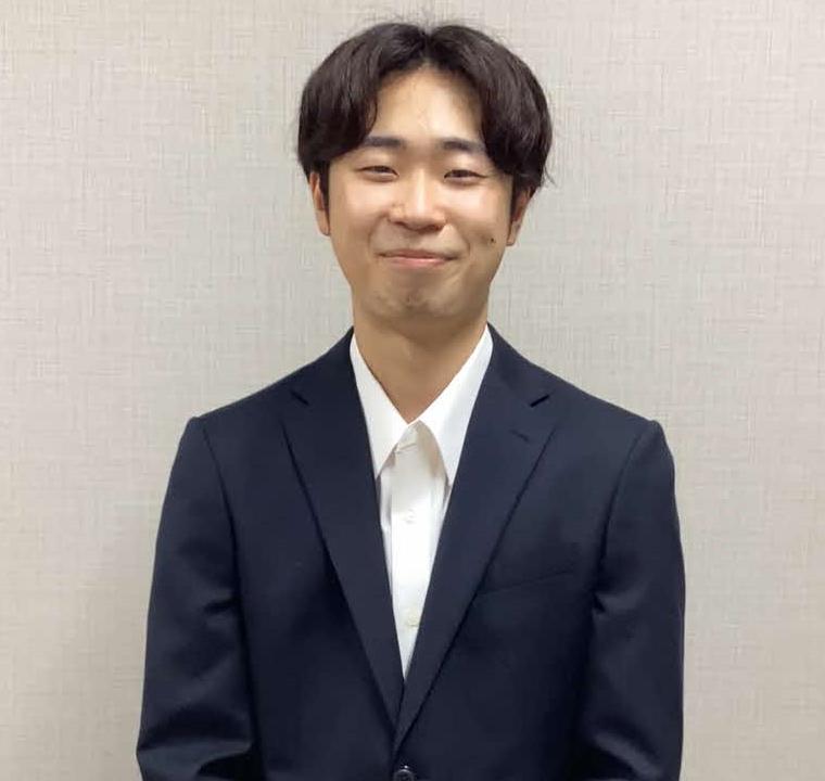 スーツを着て笑みを浮かべる卒業生の写真