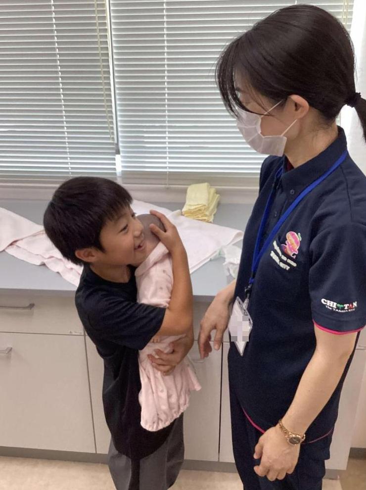 来校者の小学生が赤ちゃん人形を抱っこしているところの写真