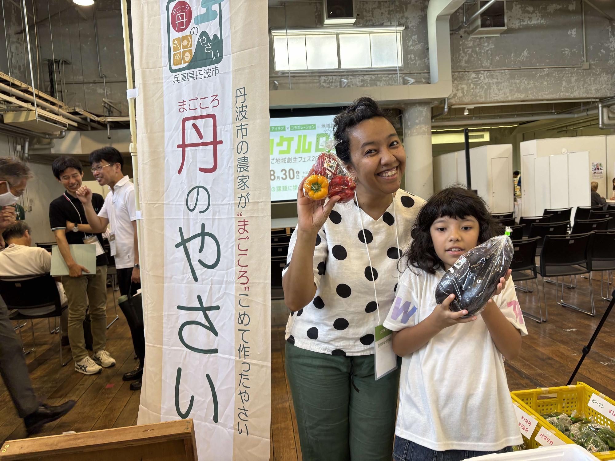 丹のやさいを手に笑顔を見せる親子