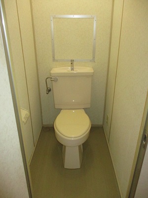 白を基調としたトイレで、床がブラウンかかった色の部屋