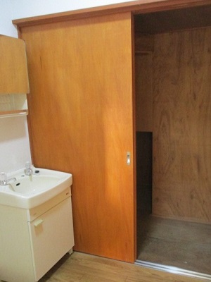 奥に木製の引き戸があり、手前に洗面台のある写真