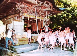 本殿の前で、半股引に上半身裸の男性十数名が、祭事を行っている写真