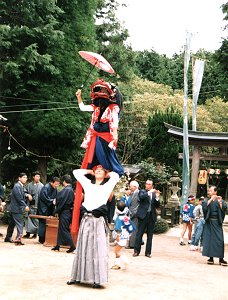 台役の肩の上に獅子が立ち、傘をさしている写真