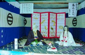 成松造り物行事で制作された、屏風の前に和服姿で座る男女の人形の写真