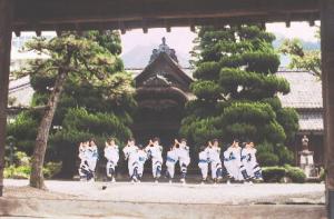 社の前で、揃いの和服を着た十数名の人々が、柏原おどりを踊っている写真
