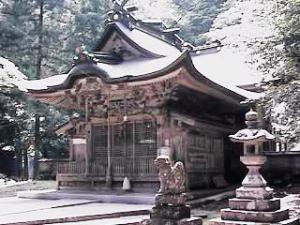 雪が積もった、狛犬越しの熊野神社社殿の写真
