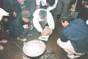 折杉神社の粥占神事(おりすぎじんじゃのかゆうらしんじ)にて、竹管を割って粥粒を数えている様子を写した写真