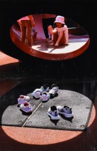 遊具の丸い穴の向こうにいる女の子と丸い明りの中にある靴をとらえた写真