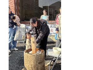 親子で杵を持って笑顔でお餅つきをしている様子