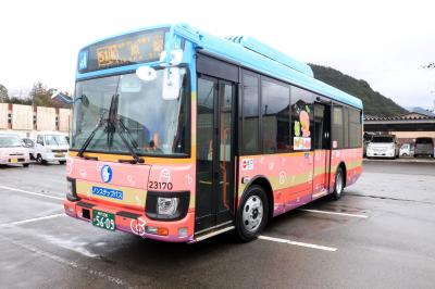 駐車場の中で、カラフルで化石のイラストが散っているバスを斜め前から写した写真