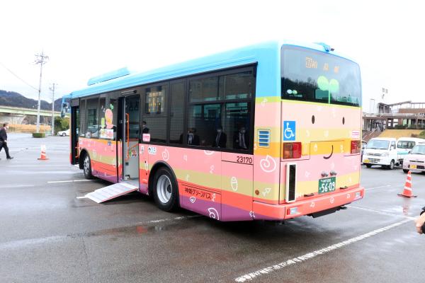 駐車場の中で、カラフルで化石のイラストが散っているバスの乗車口からスロープがわたされている写真