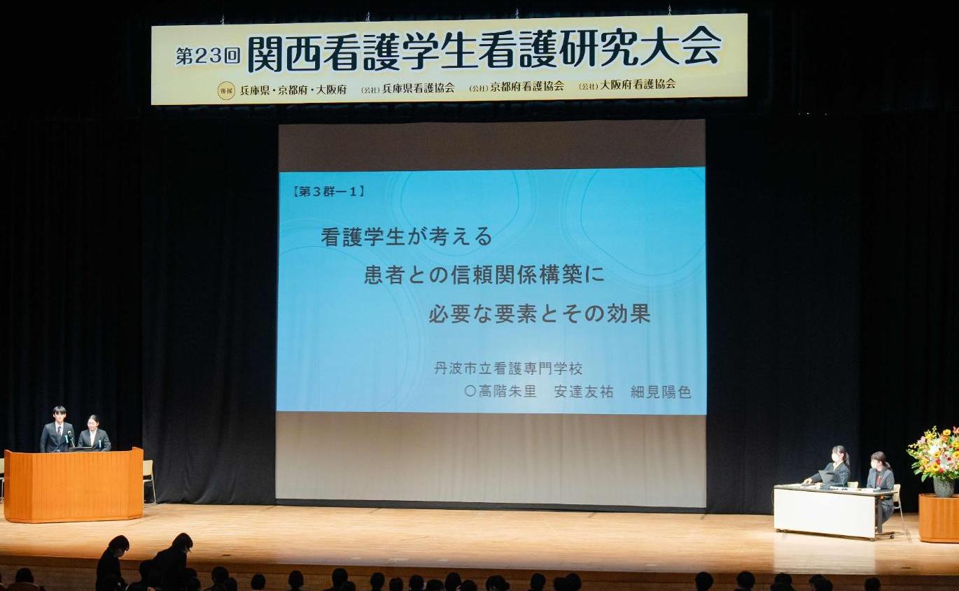 ホールの舞台上に、看護学生看護研究大会の横断幕と、スクリーンに演題が表されている写真