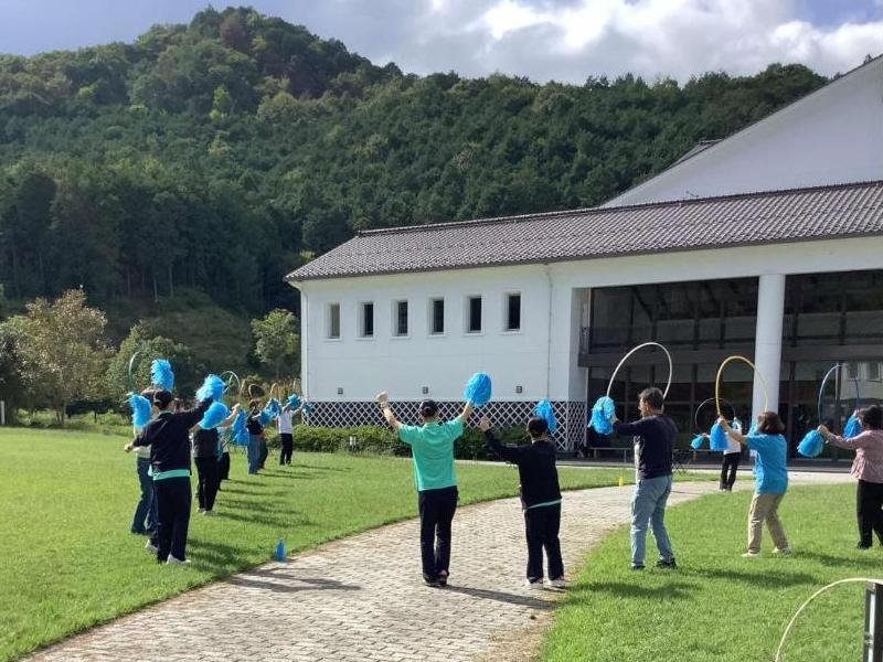 フラフープやボンボンを使ったダンスをOB大学の学生から教わっているところの写真