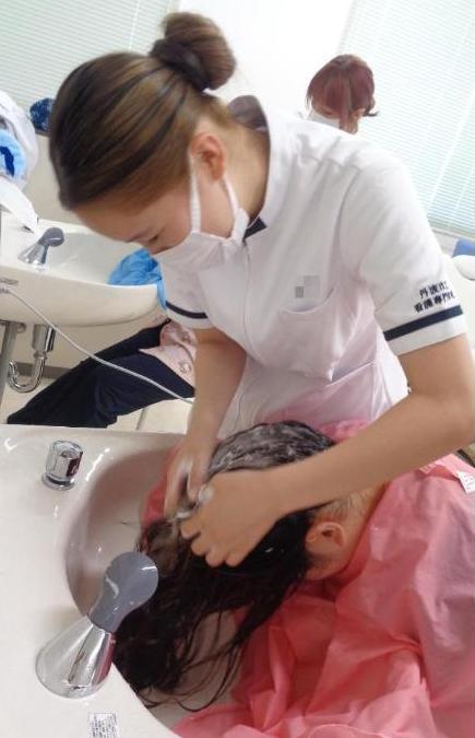 学生が洗髪台の前に座った学生の洗髪をしているところの写真