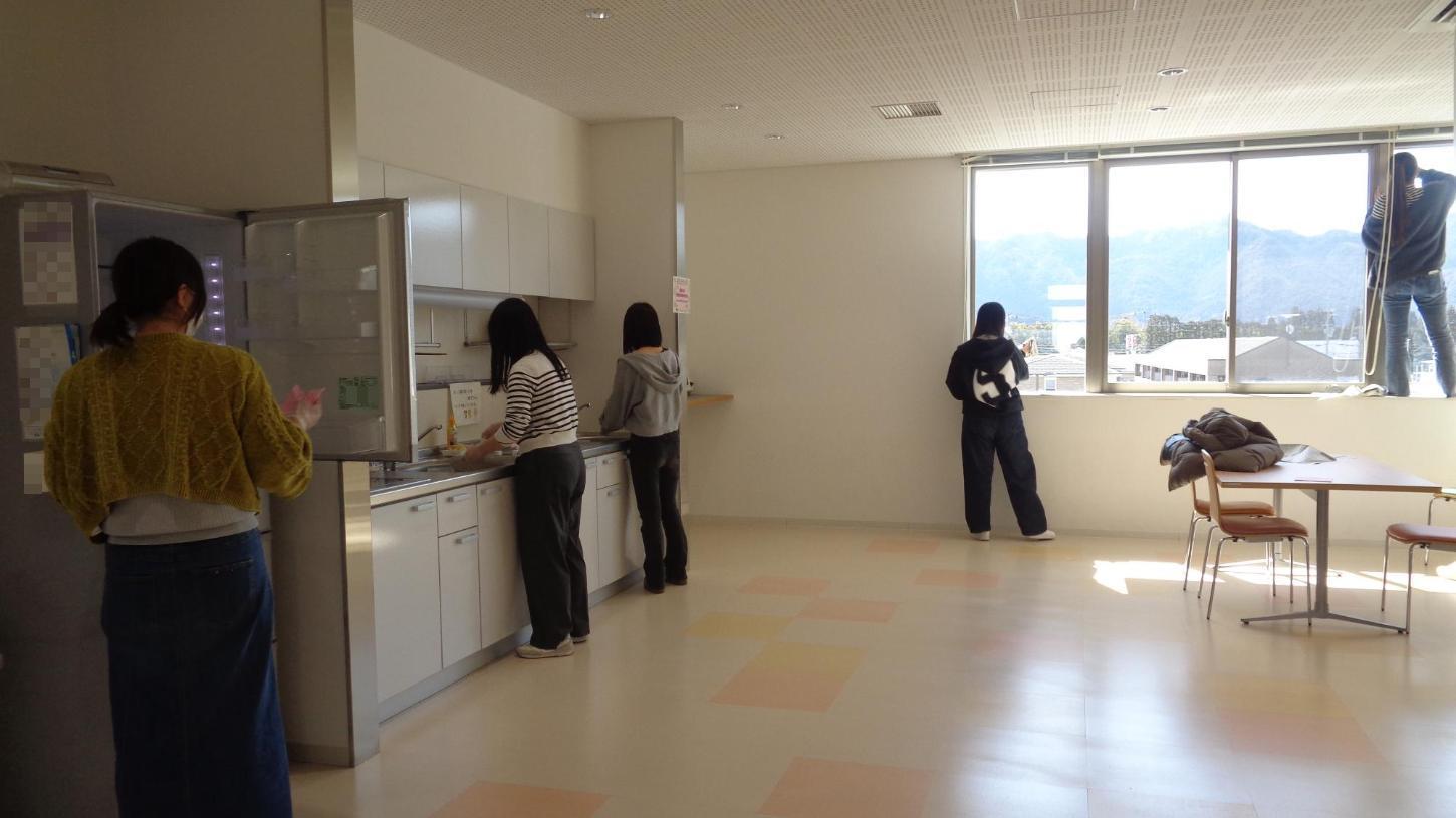 食堂の冷蔵庫の中を拭いたり、シンク周りや窓ガラスを磨いたりしている学生たちの写真