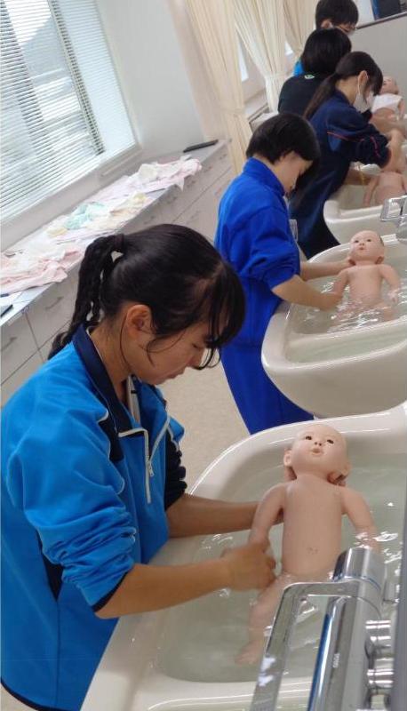 赤ちゃん人形で沐浴体験している中学生達の写真