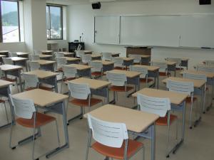 白い椅子と机が整列して並んでいる教室の写真