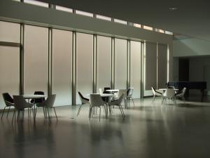 壁一面の曇りガラスから光が差し込む、椅子とテーブルが設置された談話コーナーの写真