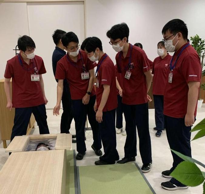 葬儀社で棺桶体験をしている学生達の写真