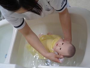 赤ん坊の人形を沐浴させている看護学生の手元の写真