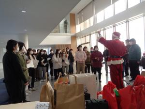 サンタクロースの男性が生徒たちの前で手を上げている写真