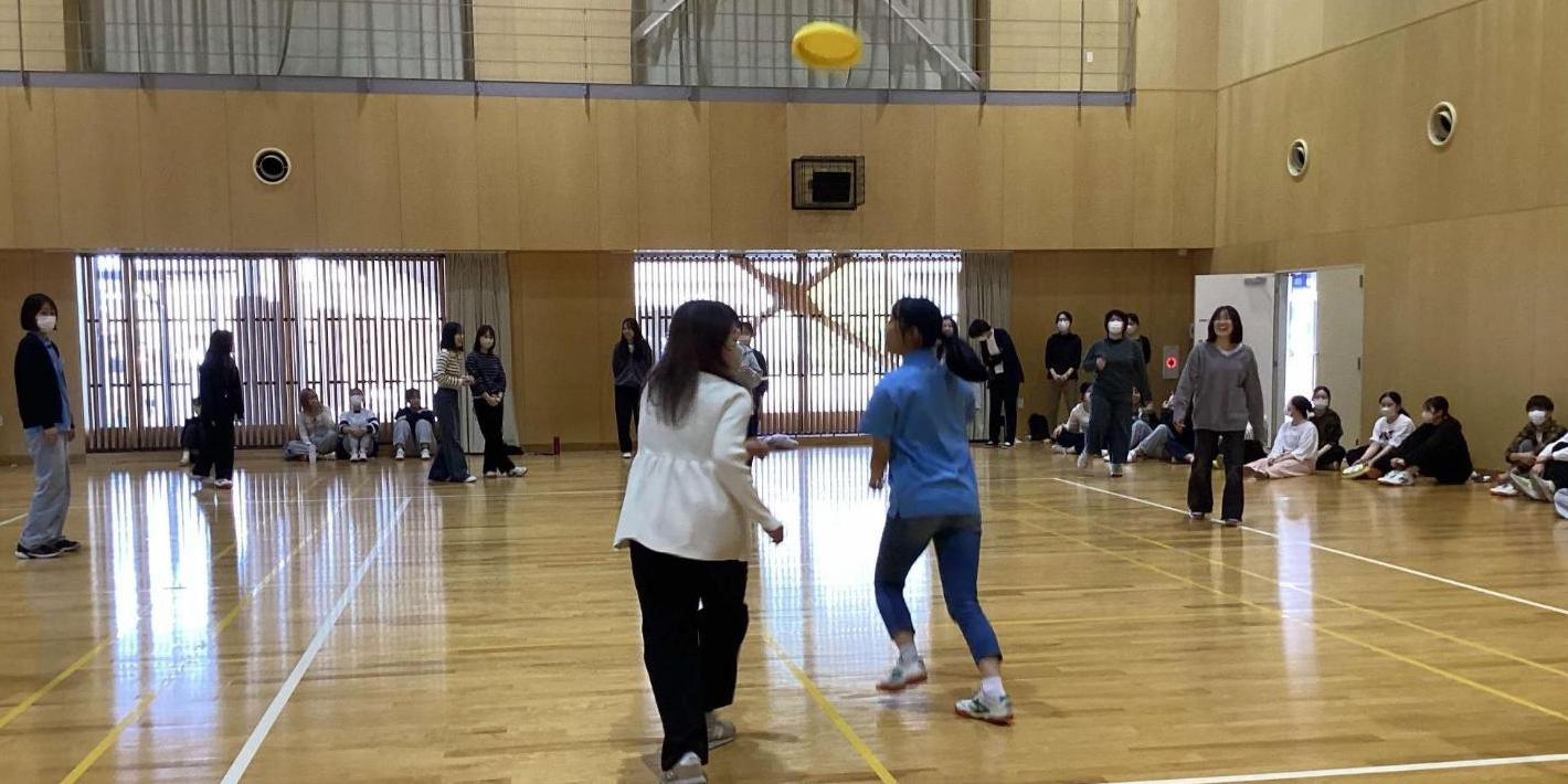 上に上がっているフリスビーに当たらないように移動している学生たちの写真