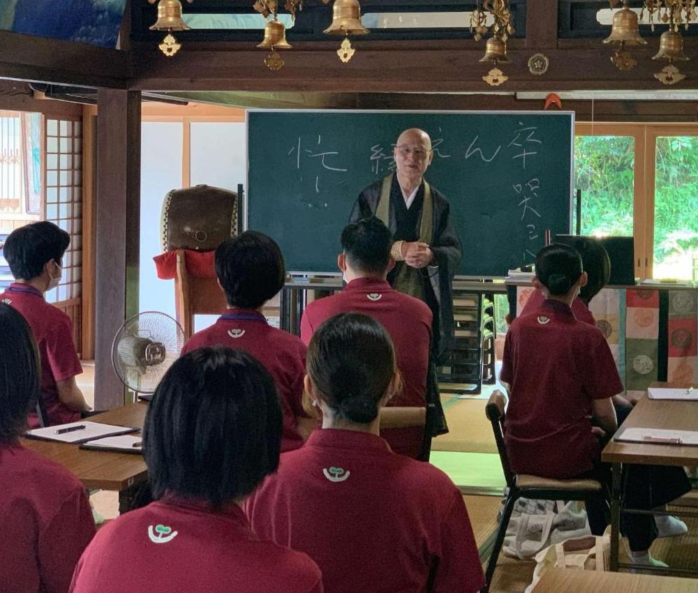 寺院で故人をしのぶ家族の心理的変化やグリーフケアの実際を教わっている学生達の写真