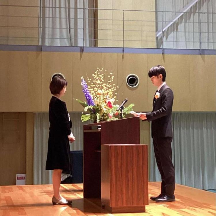 壇上で校長の向かいの卒業生が「卒業生の言葉」を話しているところの写真