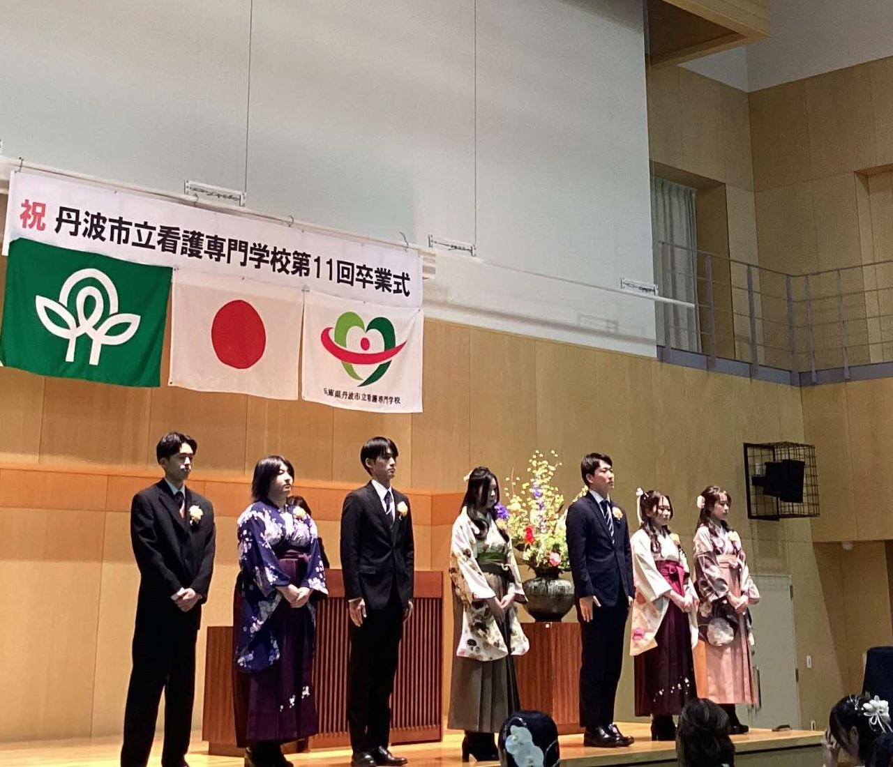 校長から特別賞をいただいた袴やスーツを着た卒業生7人が壇上で一列に並んでいるところの写真