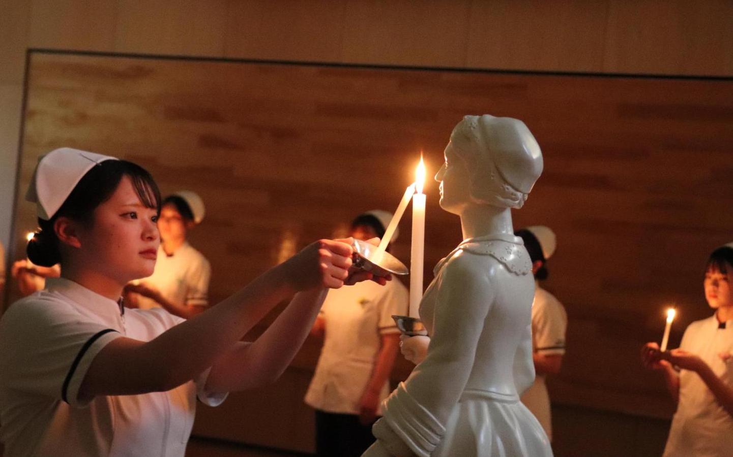 ナイチンゲール像のキャンドルに灯った火を学生が受け取っているところの写真