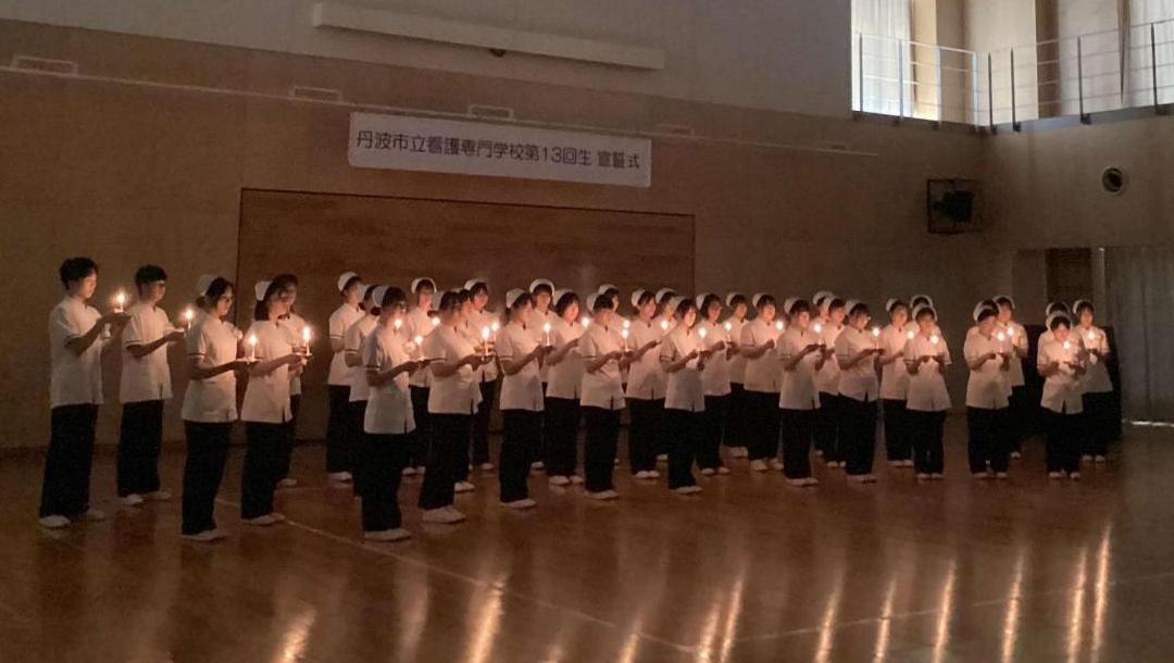 ナイチンゲール像が持つキャンドルに灯ったともしびを学生全員が受け取った集合写真