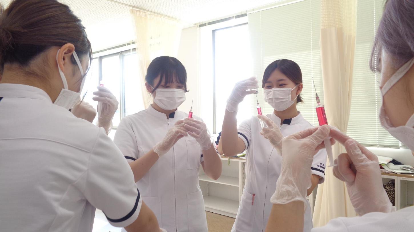 注射器の中に空気が入っていないか確認している学生たちの写真