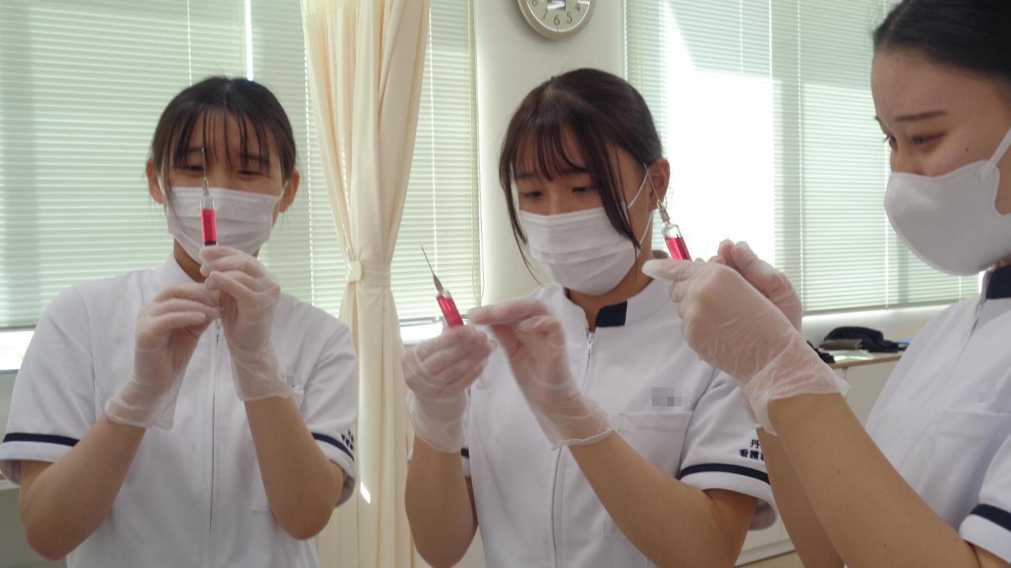 注射器の中に入ってしまった空気を除去している学生たちの写真