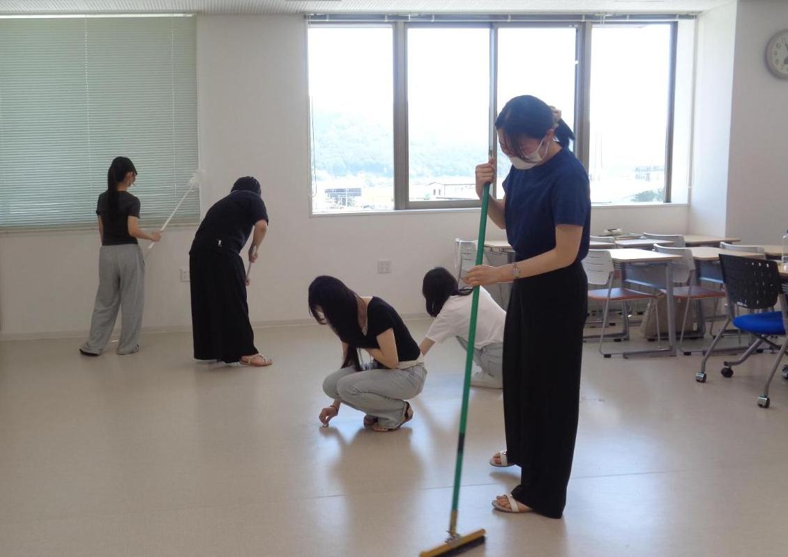 教室の床の汚れを拭き、ブラインド掃除をしている学生たちの写真