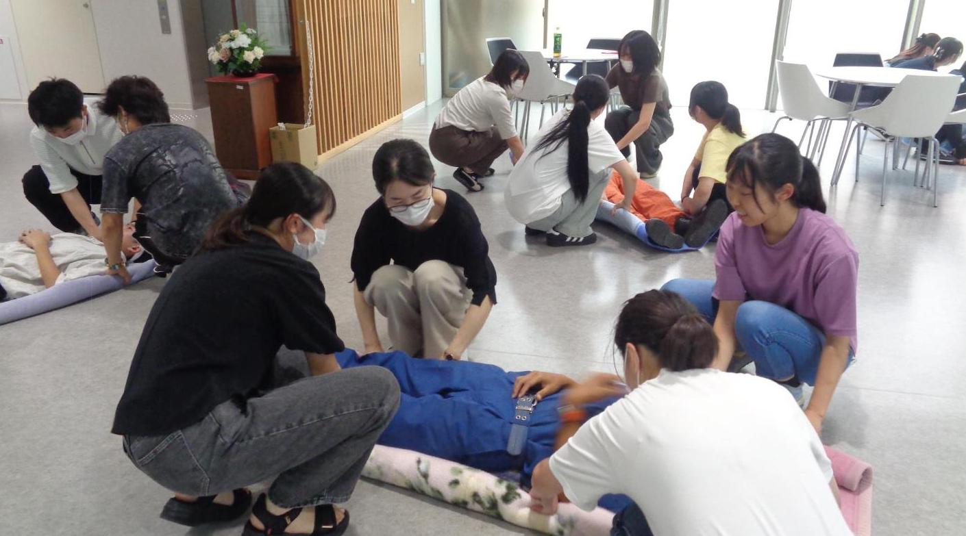 毛布を用いて4人で負傷者を搬送しようとしている学生たちの写真