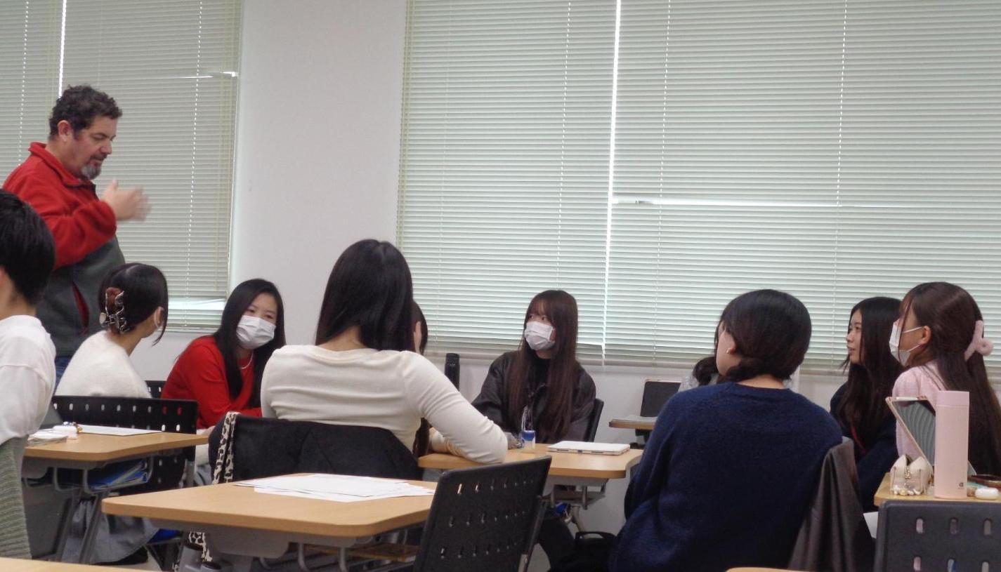 具合が悪そうにしているサンタクロースにどう対応するか？英会話講師の話を聞いている学生たちの写真