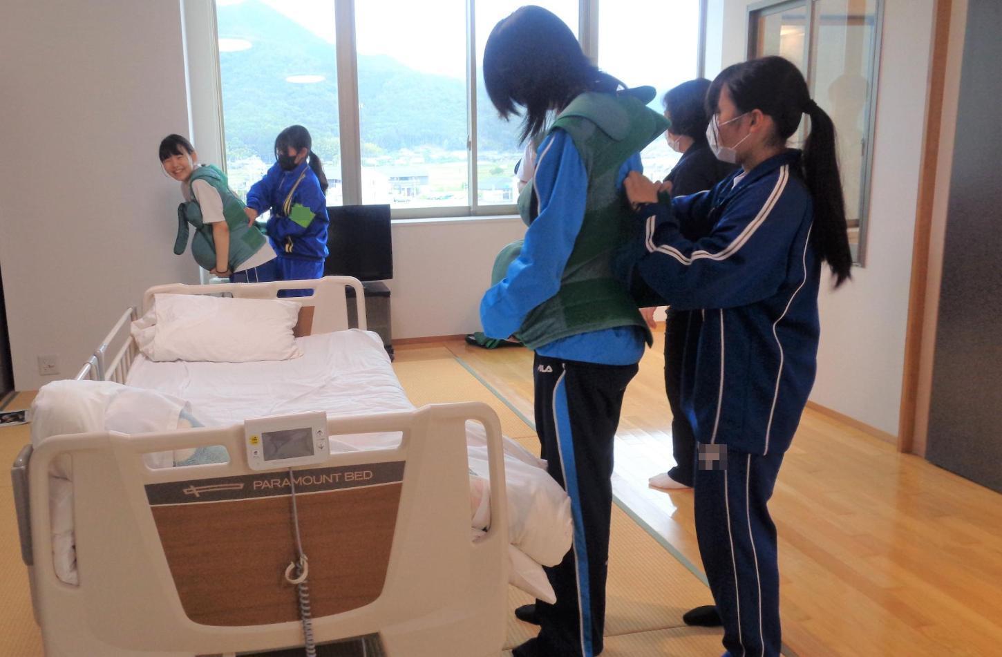 妊婦体験スーツを着せている中学生達と着せてもらっている中学生達の写真