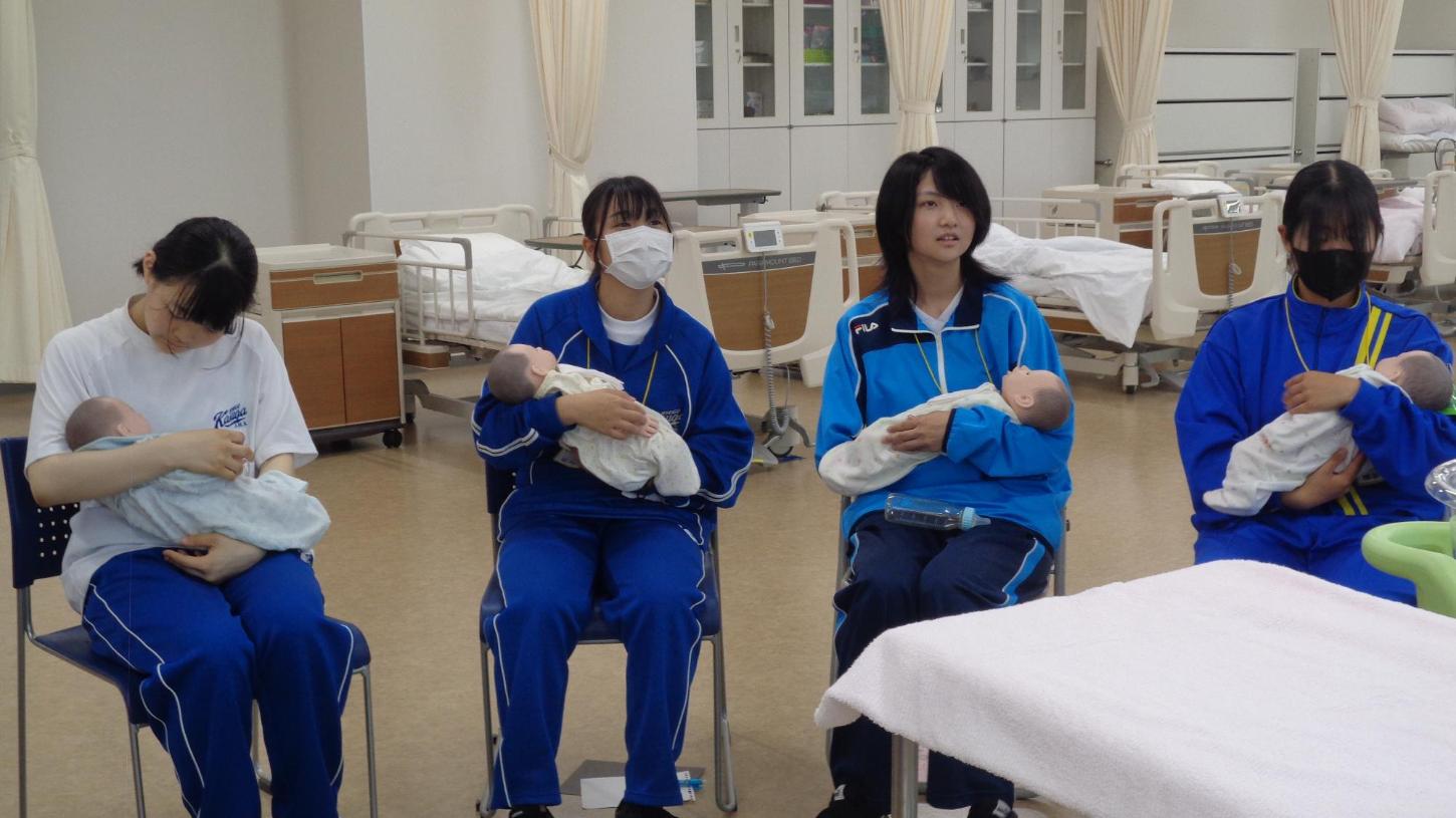 赤ちゃん人形を抱っこしている中学生達の写真