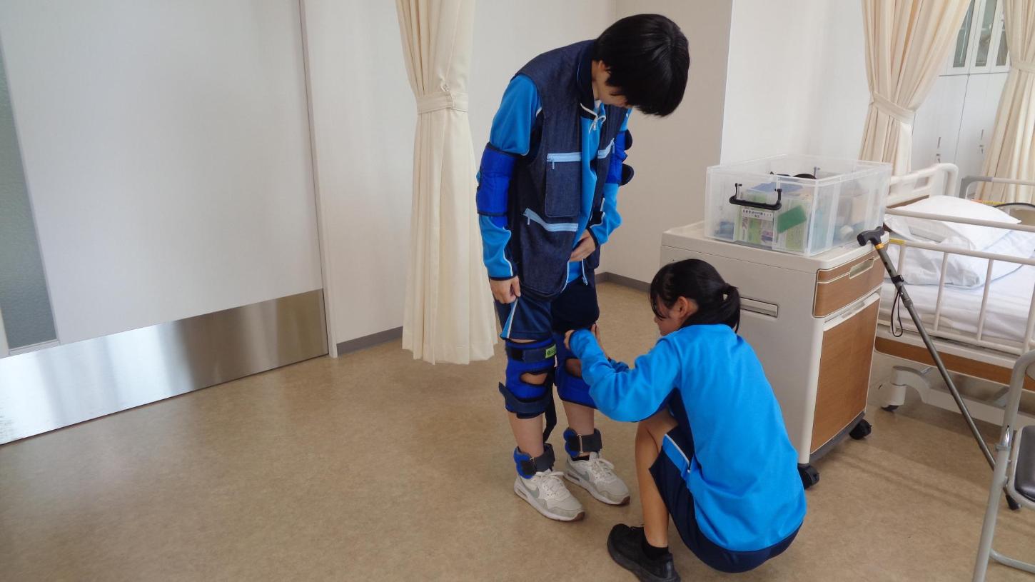 老人体験スーツを着せている中学生と着せてもらっている中学生の写真