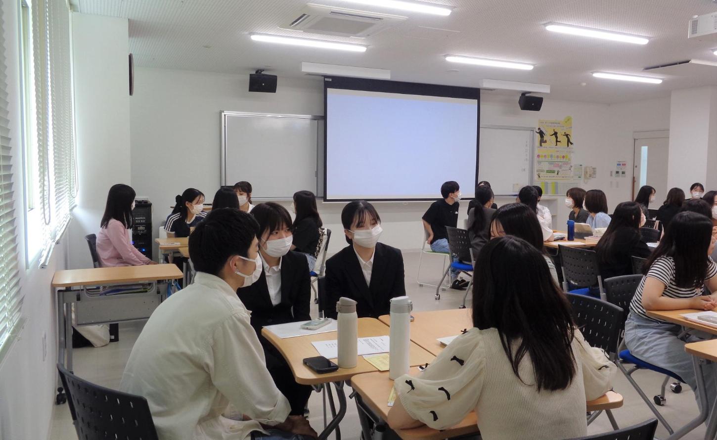 机を合わせて班になった3年生へ、卒業生が看護師の仕事の様子などを話している写真