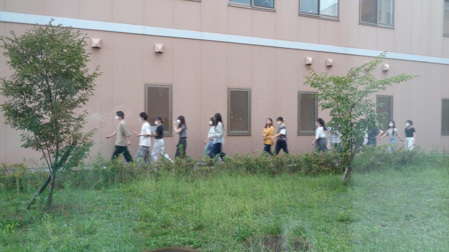 非常口から避難して、隣の健康センターミルネの建物との間を歩いている学生たちの写真